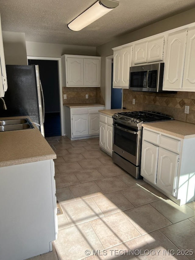 kitchen featuring white cabinets, decorative backsplash, stainless steel appliances, and sink