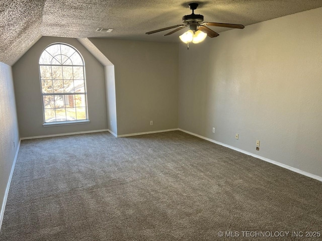 carpeted empty room featuring a textured ceiling, ceiling fan, and vaulted ceiling