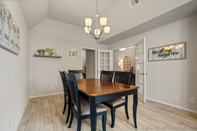 dining room featuring french doors, vaulted ceiling, light hardwood / wood-style flooring, and an inviting chandelier