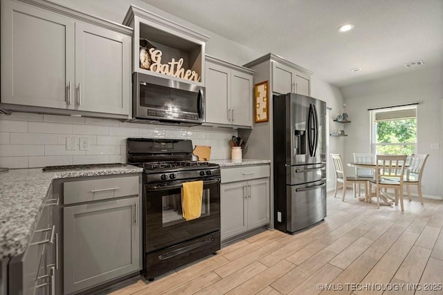 kitchen featuring light stone countertops, appliances with stainless steel finishes, decorative backsplash, and gray cabinetry