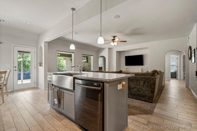 kitchen featuring ceiling fan, dishwasher, sink, an island with sink, and decorative light fixtures