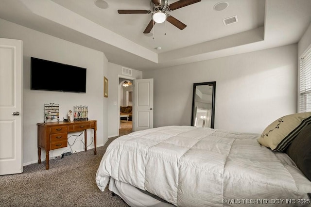 bedroom with a tray ceiling, ceiling fan, and carpet flooring