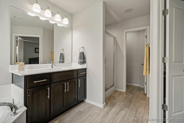 bathroom with hardwood / wood-style floors, vanity, and shower with separate bathtub