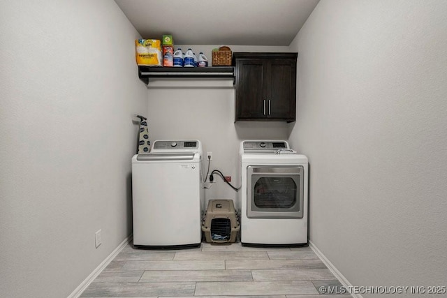 clothes washing area featuring cabinets, light wood-type flooring, and washing machine and clothes dryer