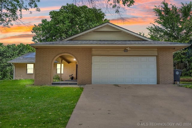 view of front of home with a garage and a lawn