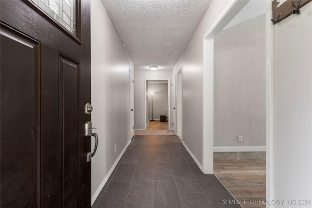 corridor with a textured ceiling and dark tile patterned floors