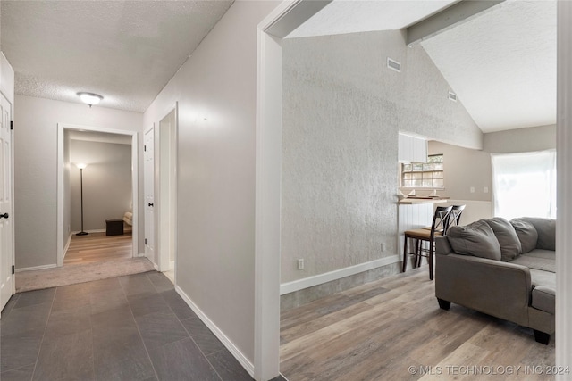 hallway featuring hardwood / wood-style floors, vaulted ceiling with beams, and a textured ceiling