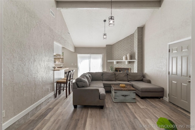 living room with wood-type flooring, high vaulted ceiling, and a brick fireplace