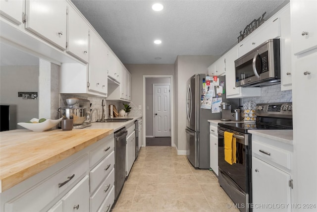 kitchen featuring decorative backsplash, stainless steel appliances, white cabinetry, and sink