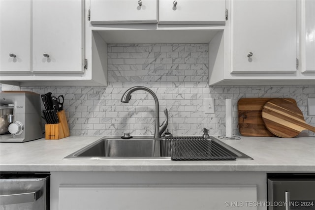 kitchen with tasteful backsplash, white cabinetry, sink, and stainless steel dishwasher