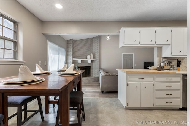 kitchen with white cabinets, a fireplace, and a textured ceiling