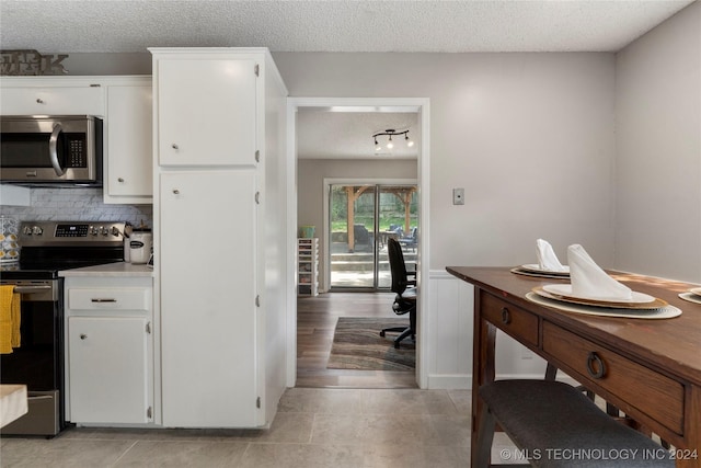 kitchen with tasteful backsplash, white cabinets, a textured ceiling, and appliances with stainless steel finishes