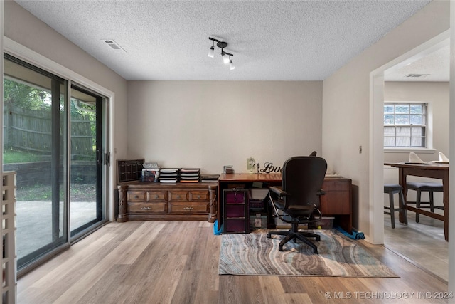 office with a textured ceiling, track lighting, and light hardwood / wood-style flooring