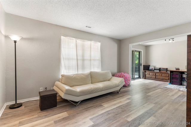 living room featuring light hardwood / wood-style flooring and a textured ceiling