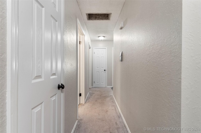 hallway featuring a textured ceiling and light colored carpet