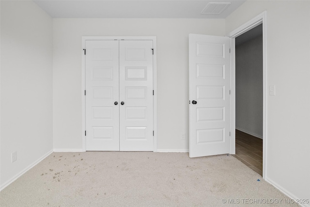 unfurnished bedroom featuring light colored carpet and a closet