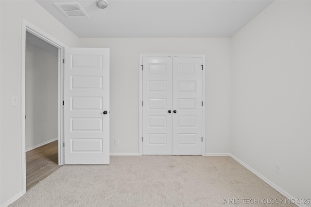 unfurnished bedroom with light carpet and a closet