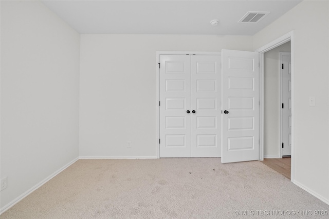 unfurnished bedroom with a closet and light colored carpet