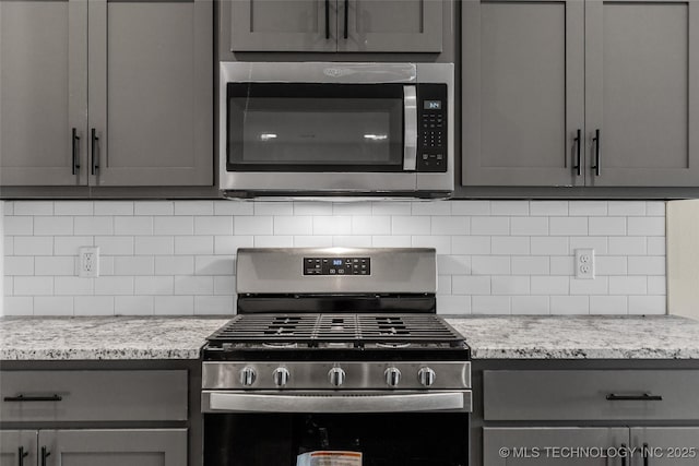 kitchen with gray cabinetry, decorative backsplash, and appliances with stainless steel finishes