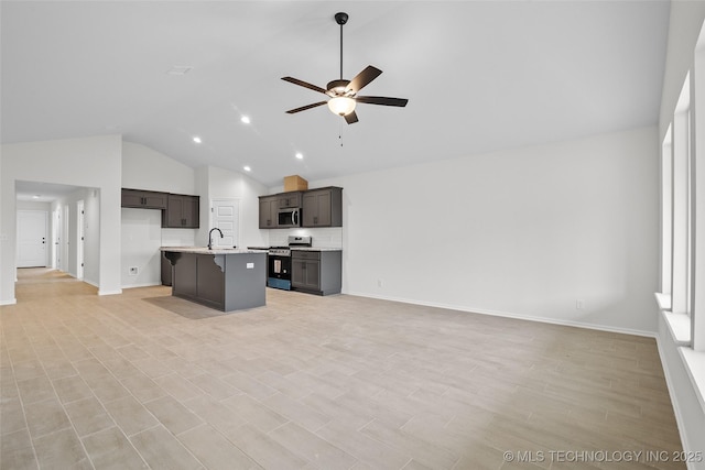 kitchen with ceiling fan, sink, stainless steel appliances, tasteful backsplash, and a center island with sink