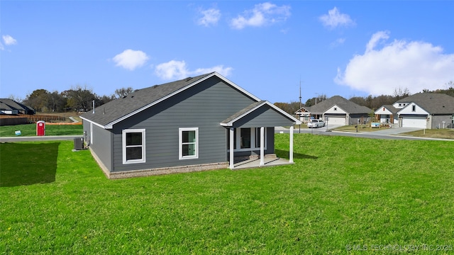 back of house with a yard, a garage, and central AC unit