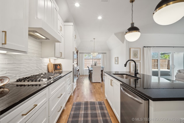 kitchen featuring stainless steel appliances, sink, decorative light fixtures, a center island with sink, and white cabinets