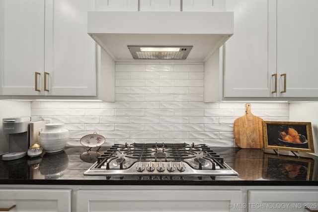 kitchen featuring tasteful backsplash, white cabinets, and ventilation hood