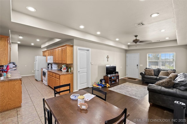 tiled dining space featuring ceiling fan and a raised ceiling