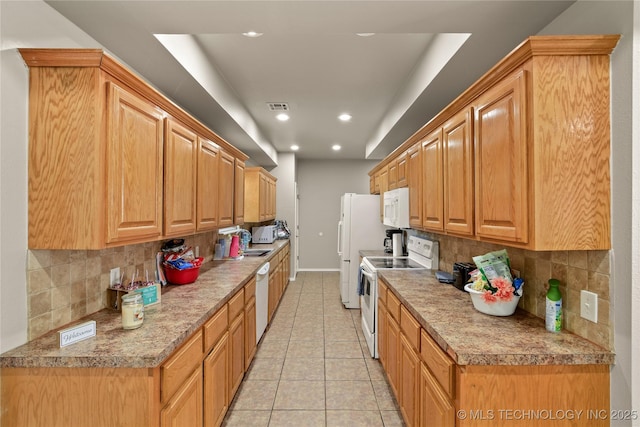 kitchen featuring decorative backsplash, sink, light tile patterned floors, and white appliances