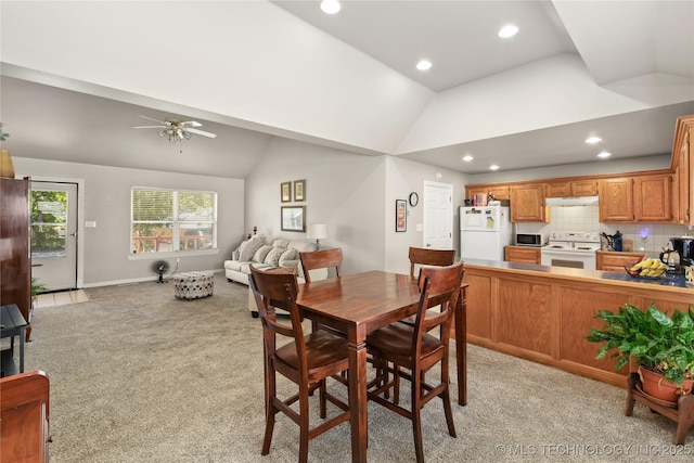 carpeted dining space with ceiling fan and lofted ceiling