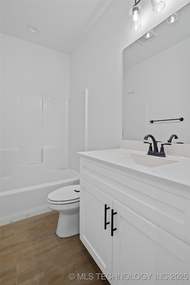 full bathroom featuring vanity, wood-type flooring, shower / washtub combination, and toilet