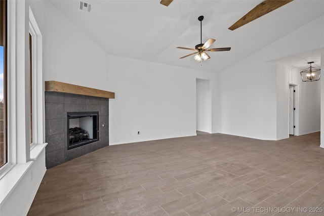 unfurnished living room featuring vaulted ceiling with beams, ceiling fan with notable chandelier, and a fireplace