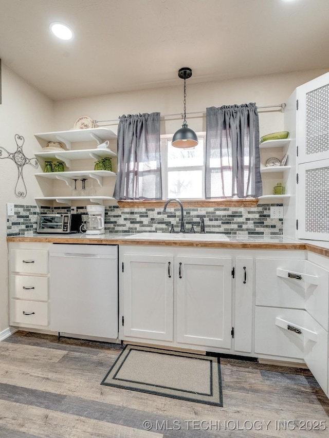 kitchen featuring light wood-type flooring, white dishwasher, sink, decorative light fixtures, and white cabinets