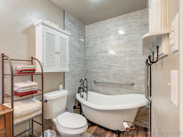 bathroom with hardwood / wood-style floors, a washtub, toilet, and a textured ceiling