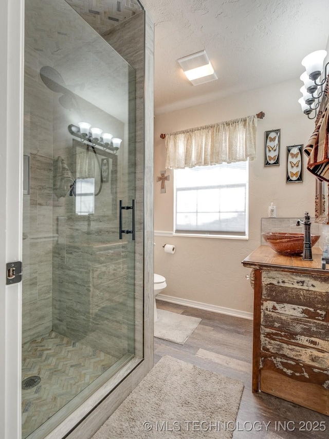 bathroom with a textured ceiling, sink, hardwood / wood-style flooring, toilet, and a shower with shower door