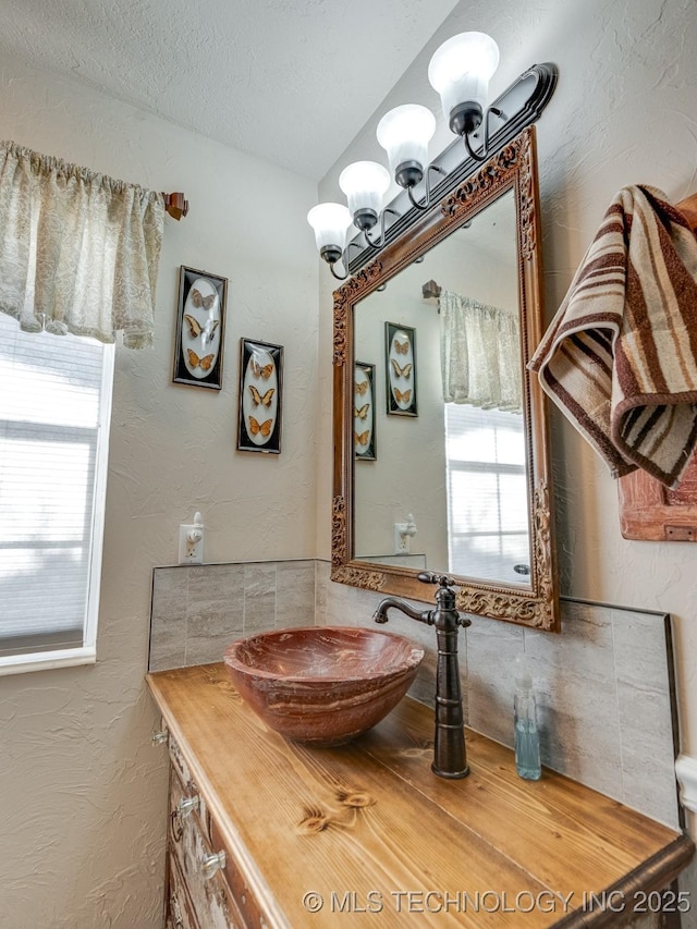 bathroom with a wealth of natural light, vanity, and a textured ceiling