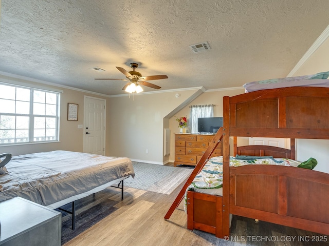 bedroom featuring a textured ceiling, ceiling fan, light wood-type flooring, and crown molding