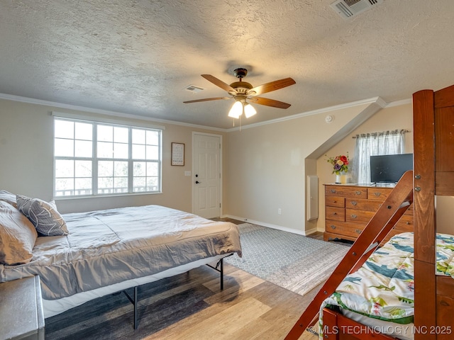 bedroom with ceiling fan, hardwood / wood-style floors, crown molding, and a textured ceiling