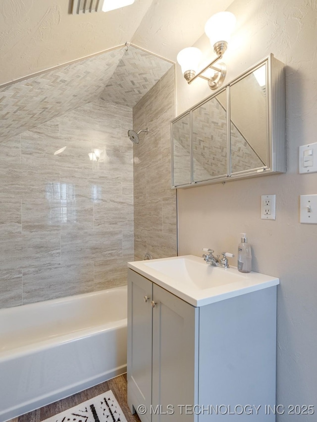 bathroom featuring hardwood / wood-style flooring, vanity, and tiled shower / bath