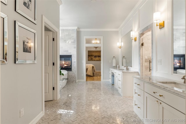 bathroom with a tile fireplace, vanity, and crown molding