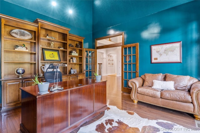 home office with dark hardwood / wood-style flooring and a towering ceiling