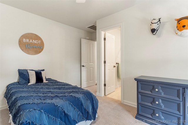 bedroom featuring connected bathroom and light carpet