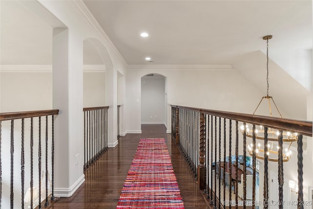 hallway with dark hardwood / wood-style flooring, crown molding, and an inviting chandelier