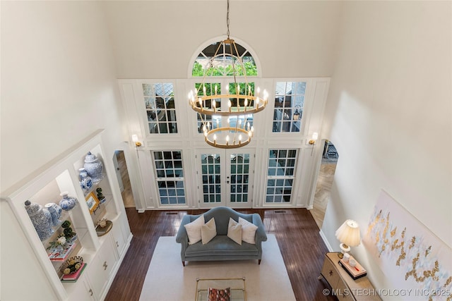 living room with french doors, a towering ceiling, dark hardwood / wood-style flooring, and a notable chandelier