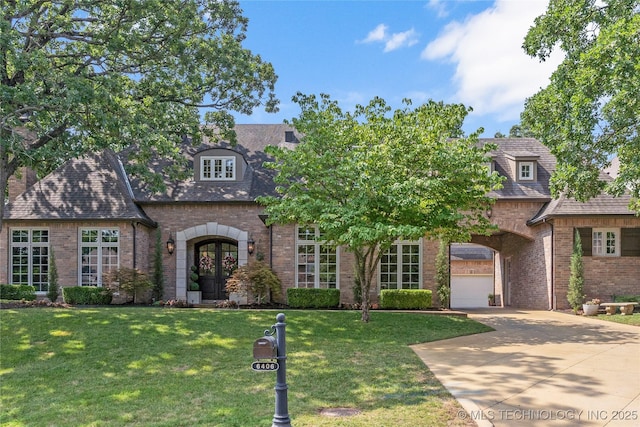 view of front of property featuring a garage, a front yard, and french doors