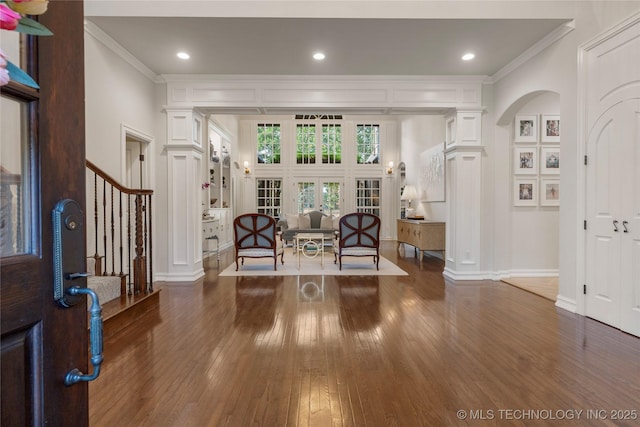 entryway with ornamental molding, dark wood-type flooring, and decorative columns