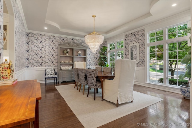 dining space with a tray ceiling, dark hardwood / wood-style flooring, plenty of natural light, and a notable chandelier