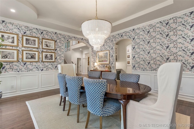 dining room featuring a chandelier, a raised ceiling, dark wood-type flooring, and crown molding