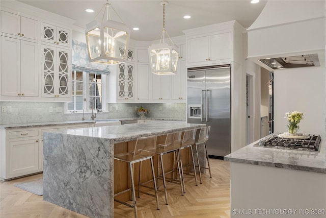 kitchen with light parquet floors, stainless steel appliances, a kitchen island, and white cabinetry