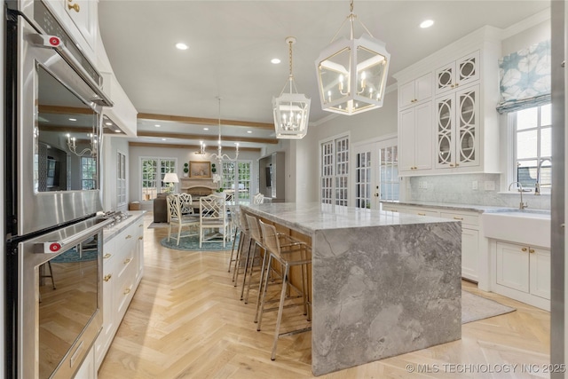 kitchen featuring light stone countertops, pendant lighting, white cabinetry, and a large island